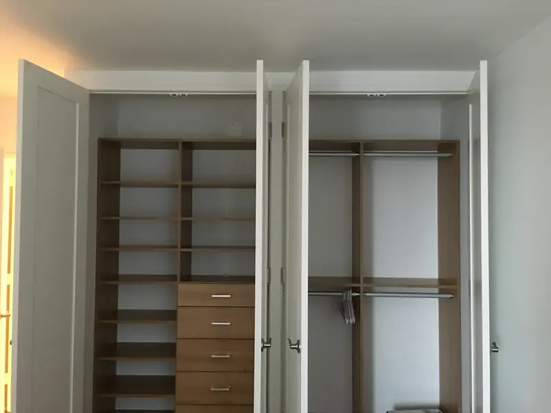 Two reach-in closets with their doors open, fitted with wood shelves, drawers and hanging rods