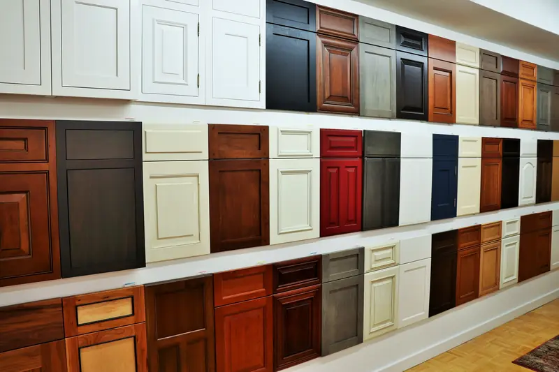 A showroom wall of cabinet door samples in white, cream, cherry, grey, red and navy